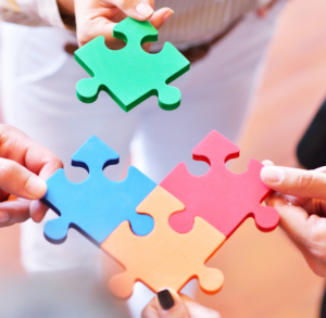 Quatre mains assemblant des pièces de puzzle, symbolisant l’intégration, la collaboration et le développement des compétences